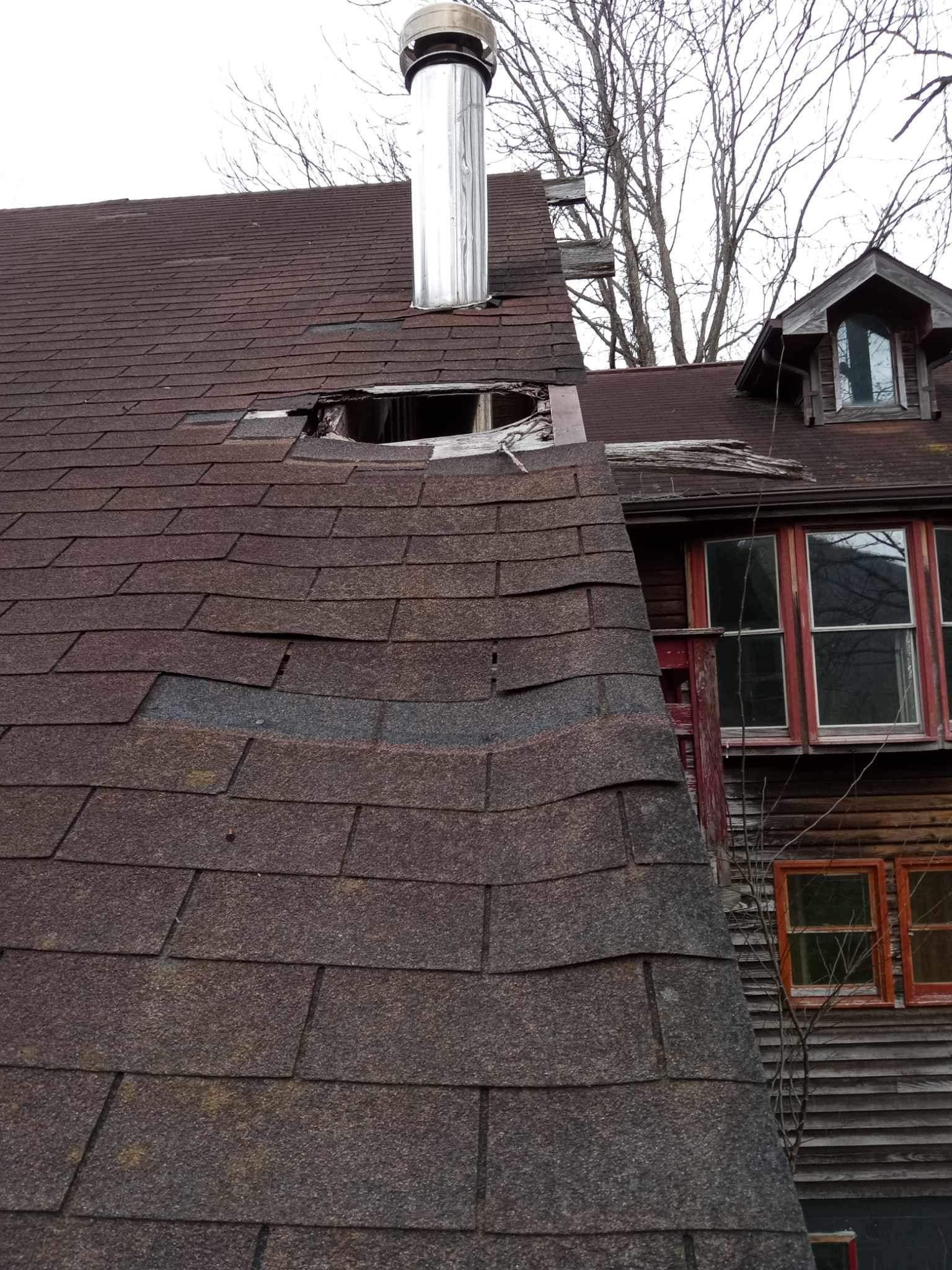 A roof with a hole in it and a chimney on top of it.
