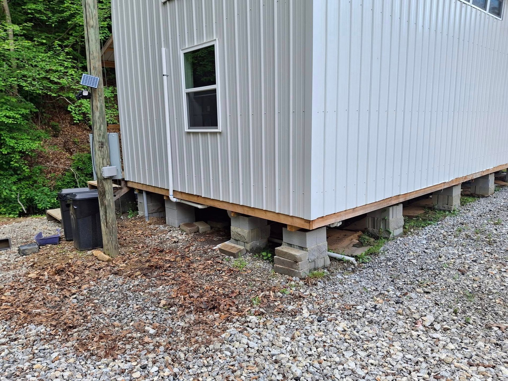 A white building is sitting on top of a gravel driveway.