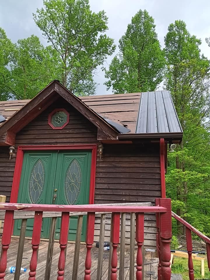 A small house with a red railing and a green door is surrounded by trees.