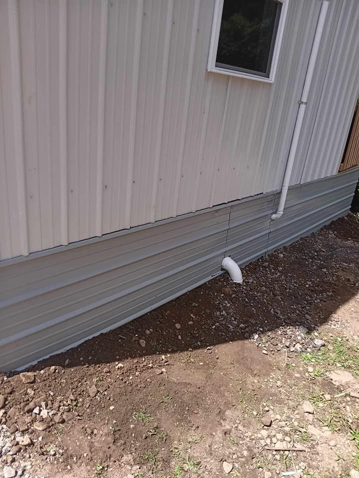 A white house with a drain pipe on the side of it.