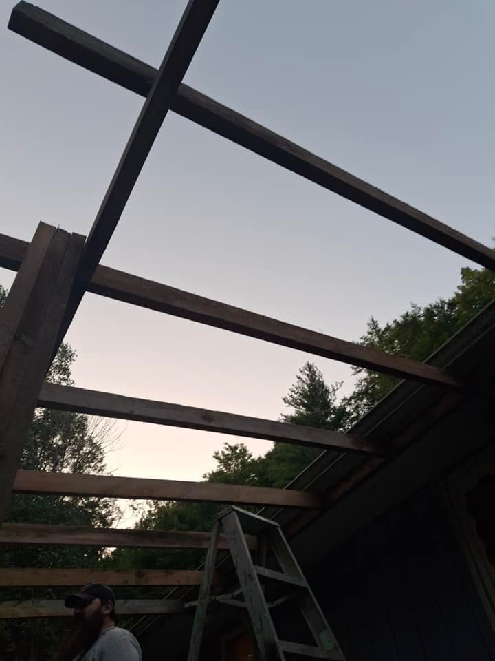 A man standing on a ladder looking up at a wooden structure