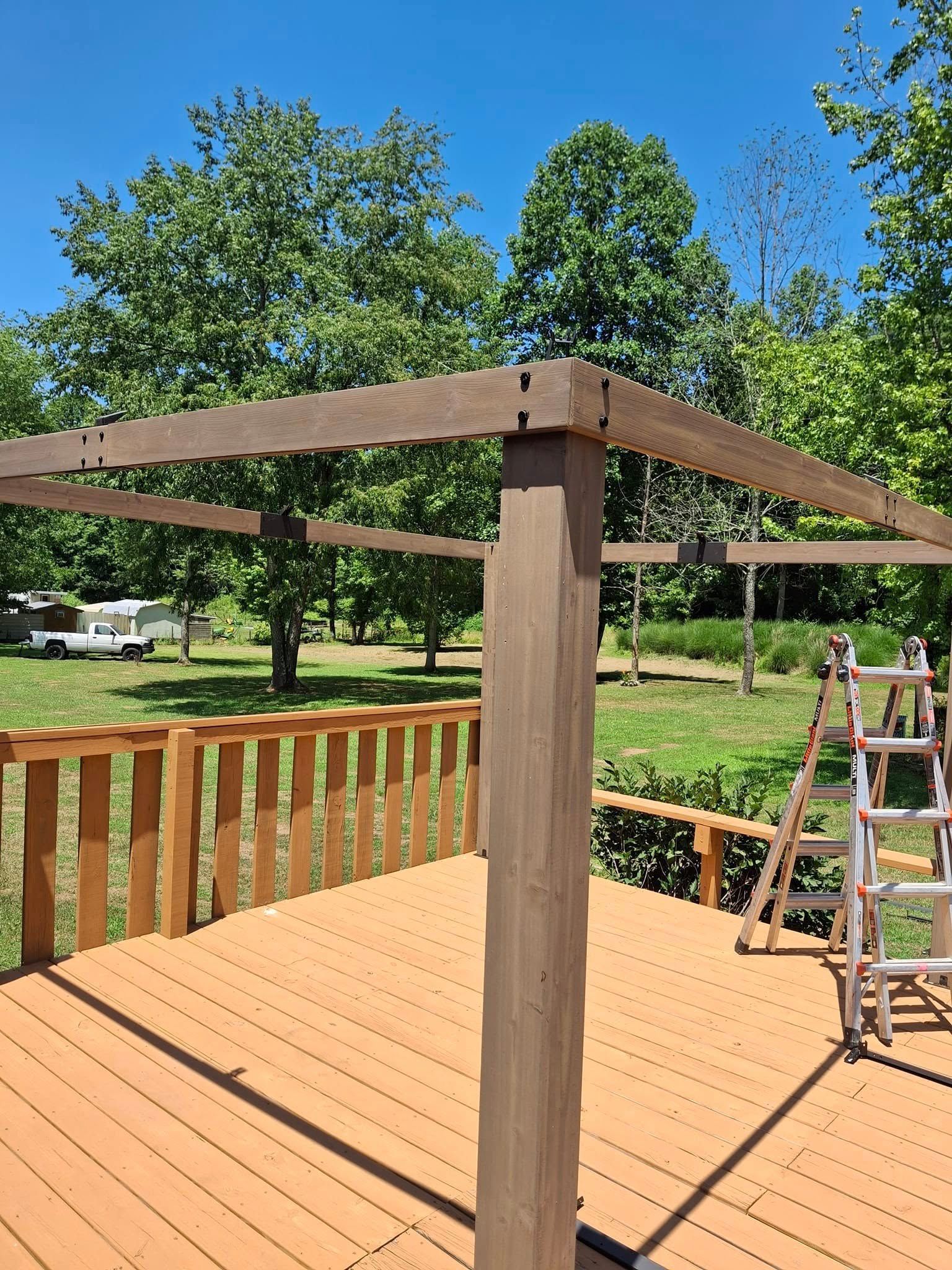 A wooden deck with a ladder on it and trees in the background.