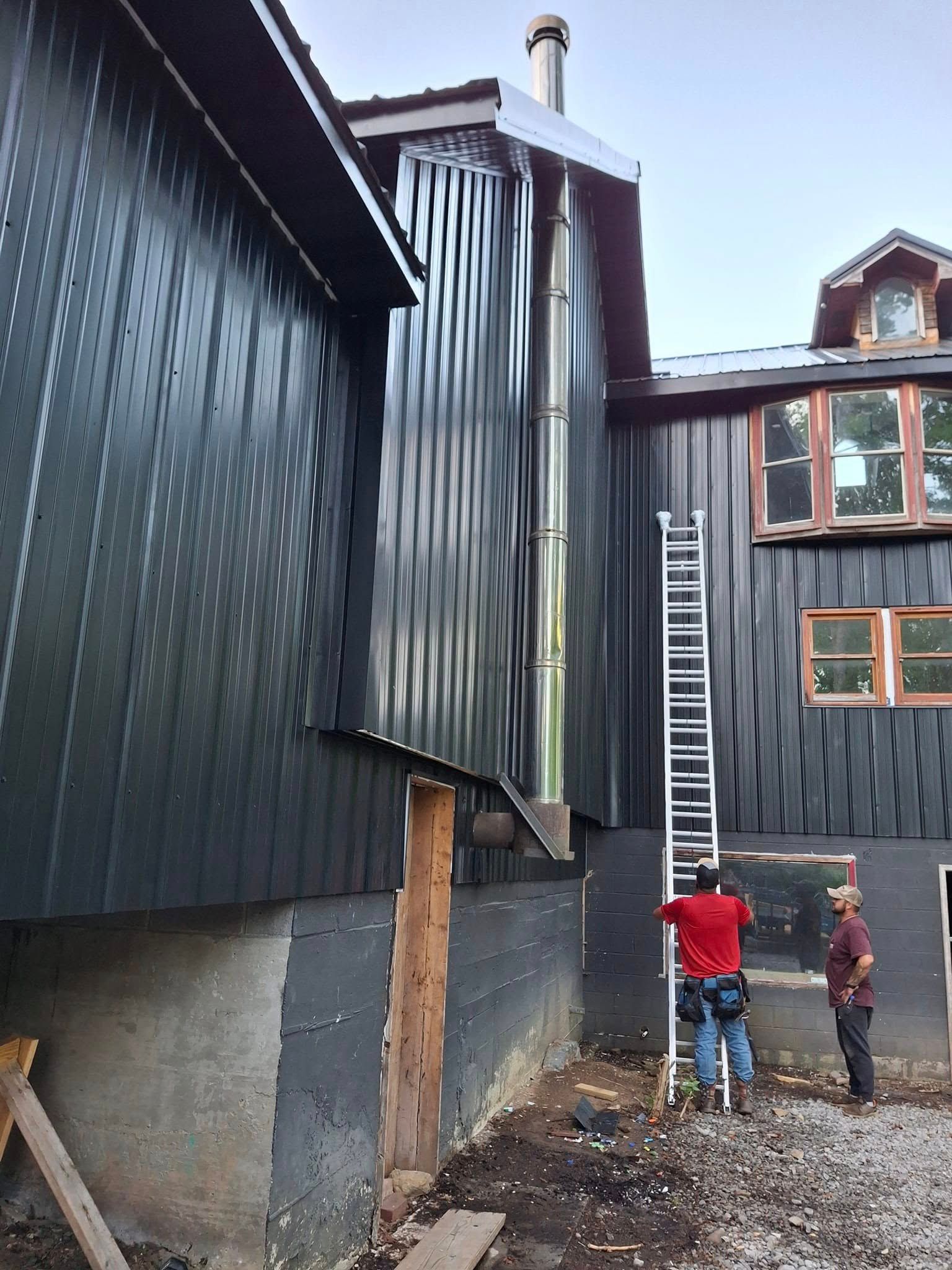 A man is standing next to a ladder in front of a building.