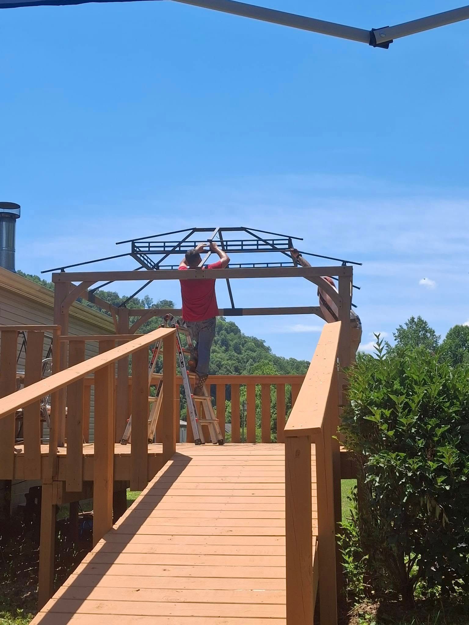 A man is working on a wooden structure on a wooden deck.