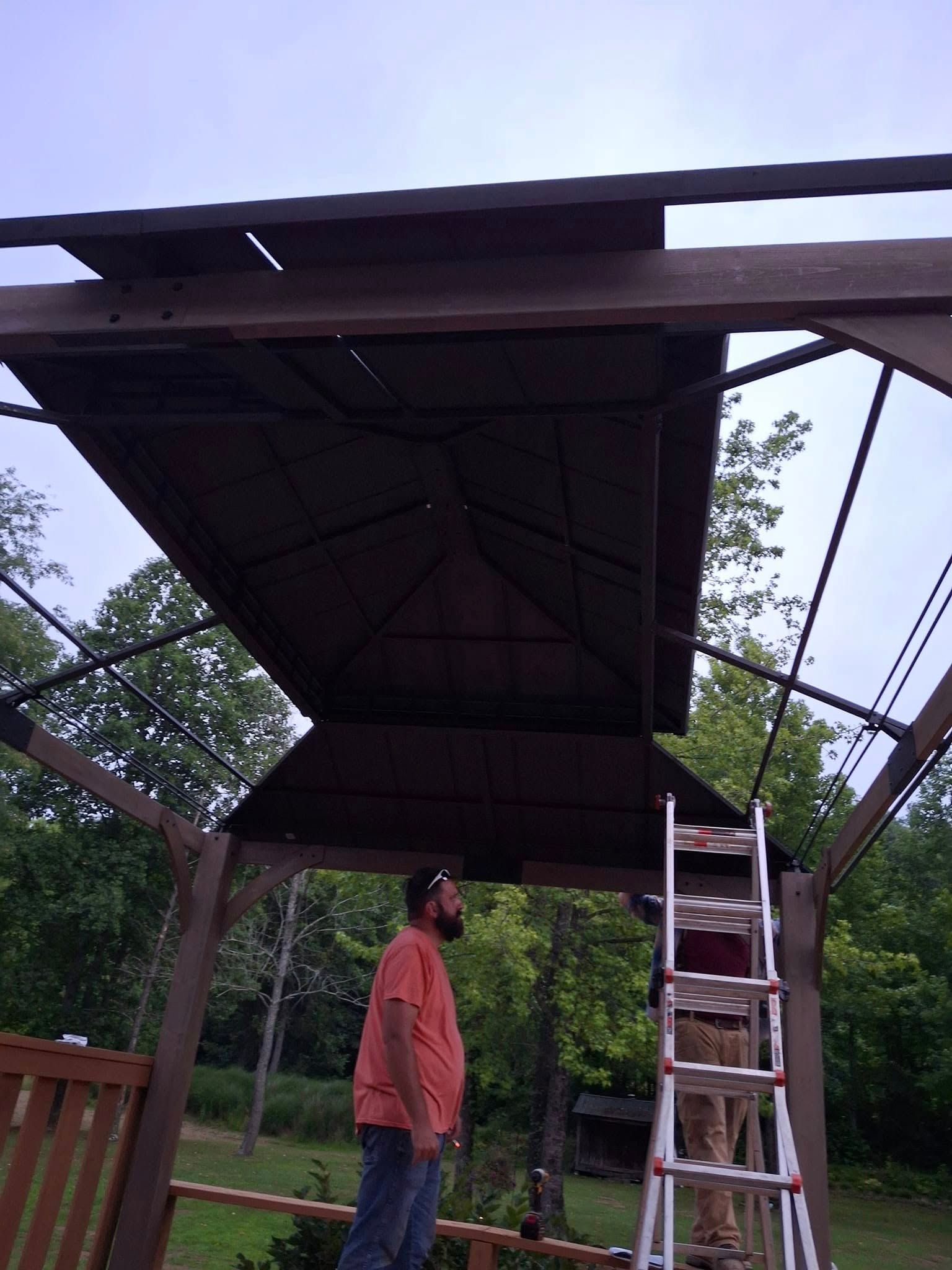 A man is standing under a gazebo with a ladder.