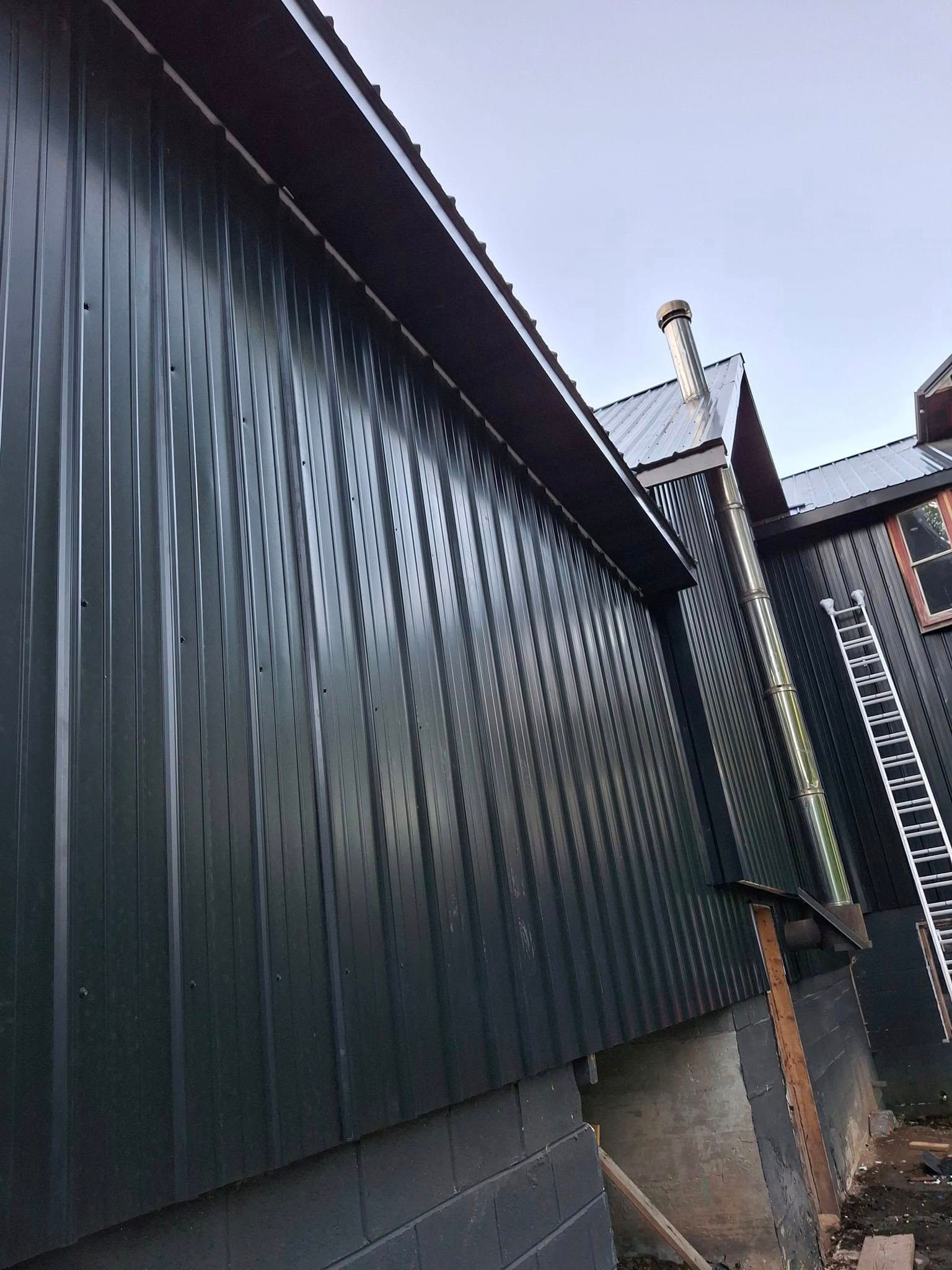 A black building with a ladder on the side of it.