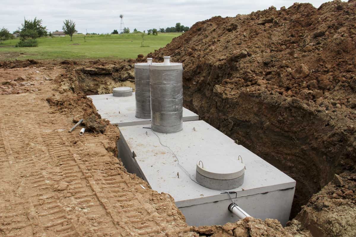 A septic tank is being built in a dirt field.