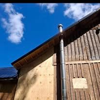 A wooden building with a metal pipe coming out of the roof.