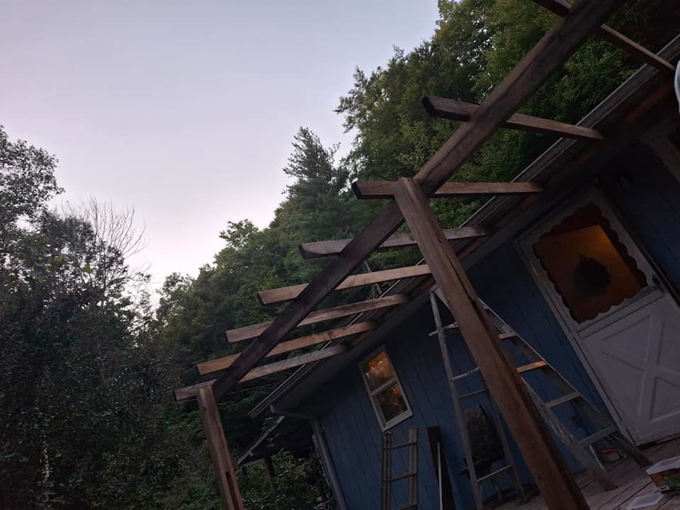 A blue house with a wooden pergola in front of it.