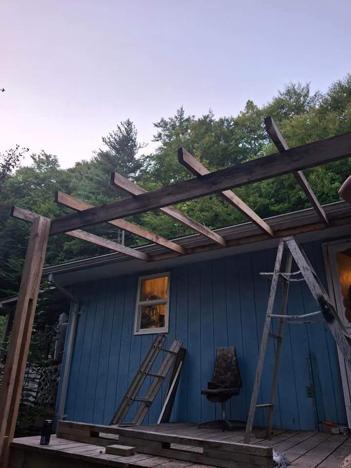 A blue house with a wooden pergola being built on top of it.