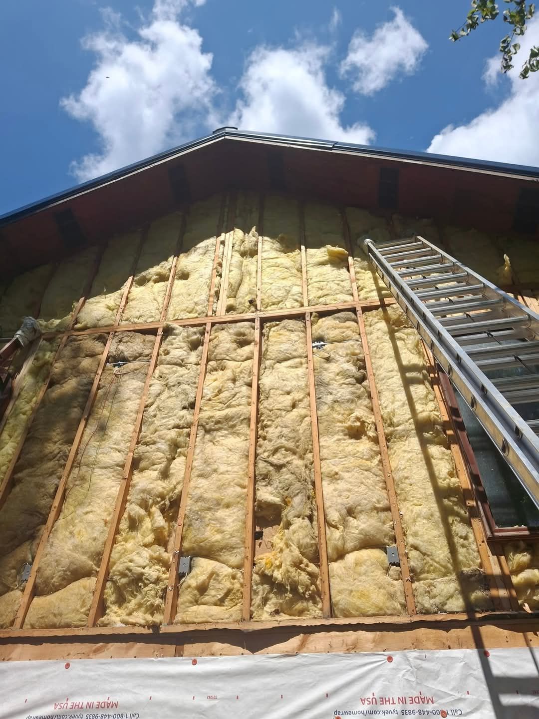 A ladder is sitting on the side of a building covered in insulation.