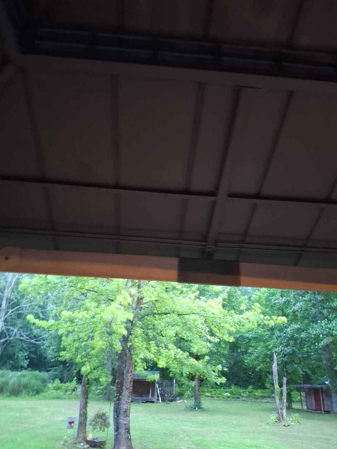 A view of a lush green field from under a roof