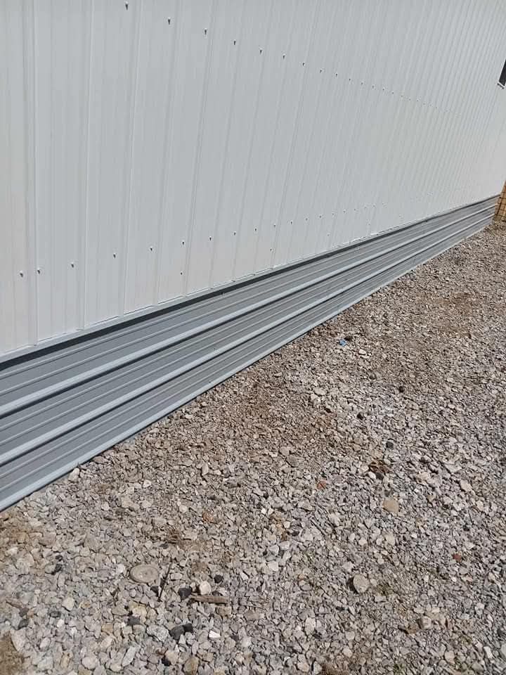 A white building is sitting on top of a pile of gravel.