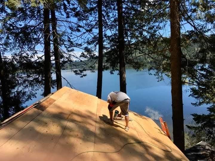 A man is working on a roof overlooking a lake