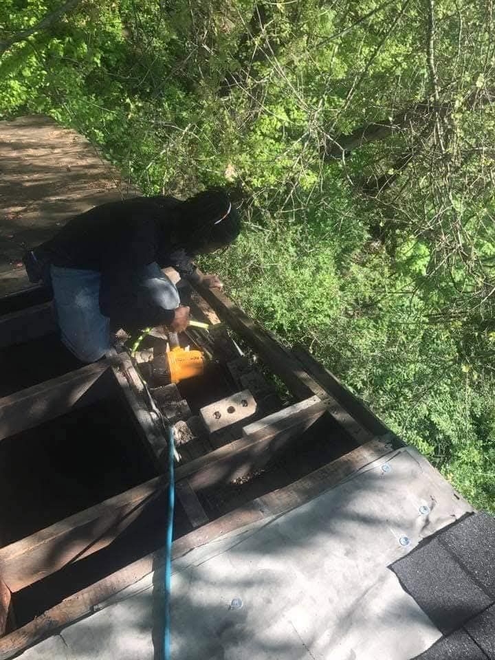 A man is working on a roof in the woods.