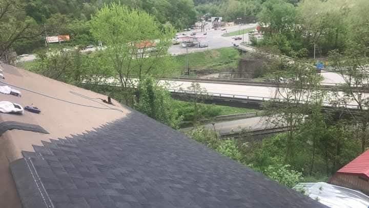 A roof is being installed on a house with a lot of trees in the background.