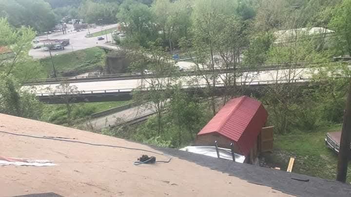 A red roof is sitting on top of a roof next to a bridge.