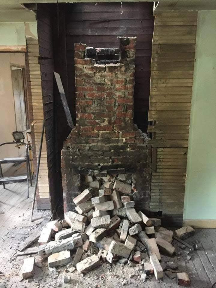 A pile of bricks is sitting in front of a brick fireplace.