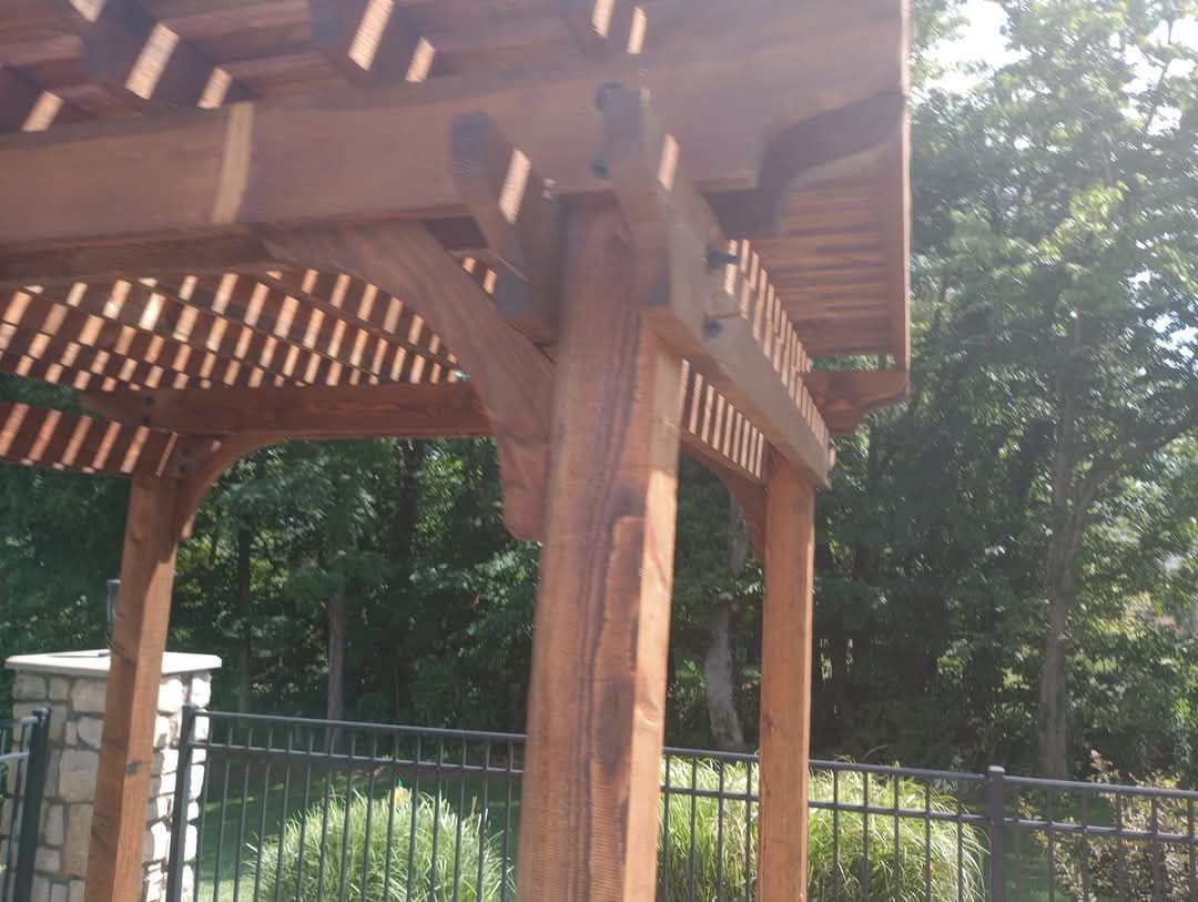 A wooden pergola with a fence in the background