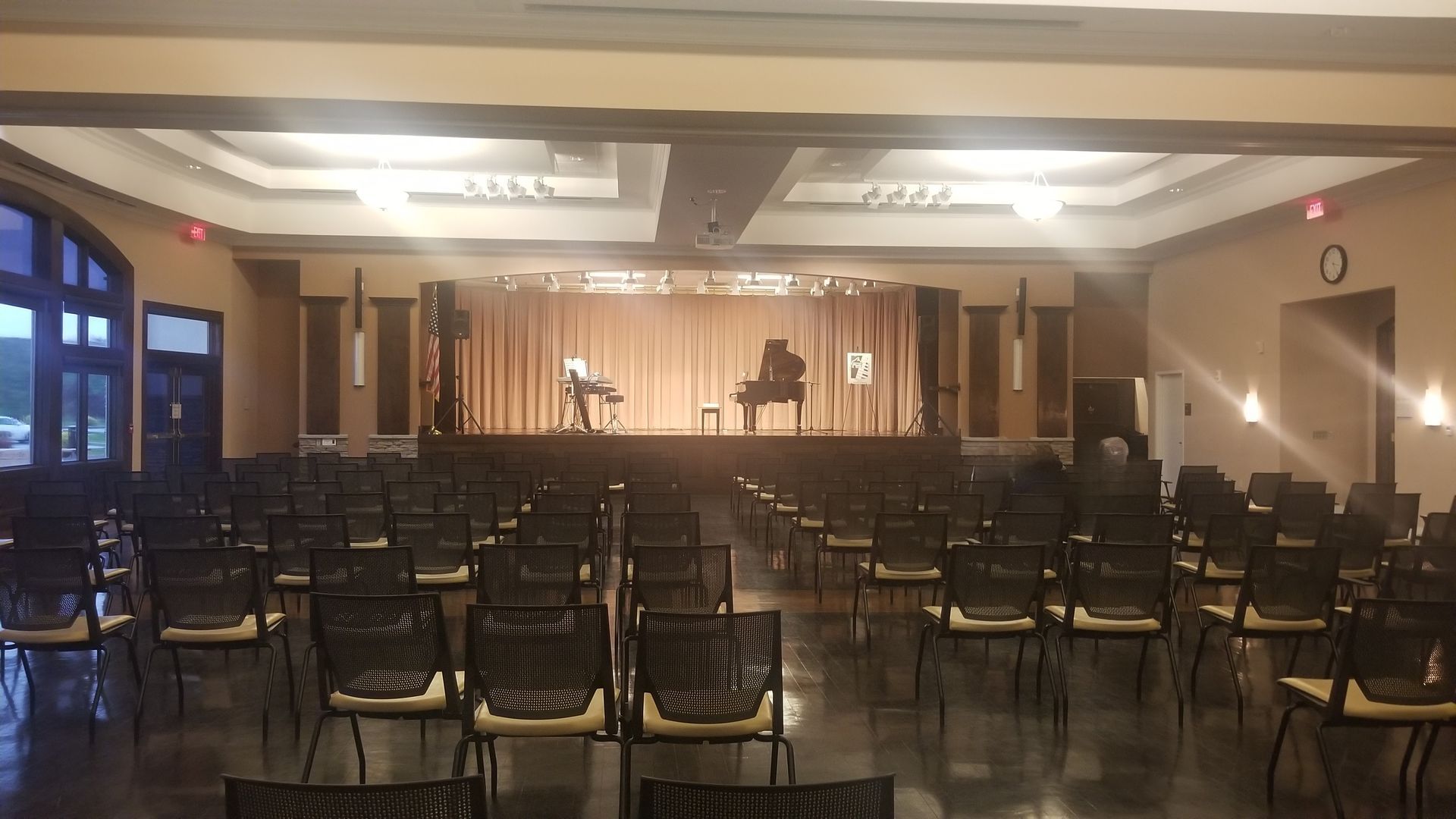 A large auditorium with rows of chairs and a piano on the stage.