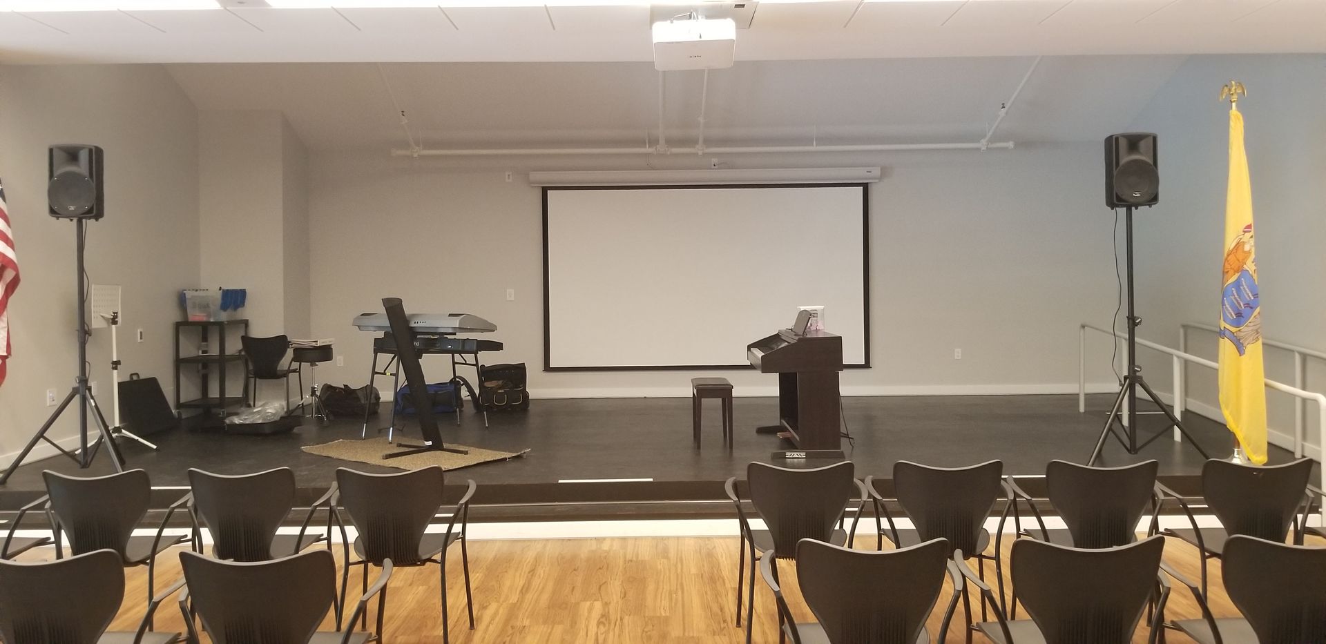 A room with rows of chairs and a projector screen.