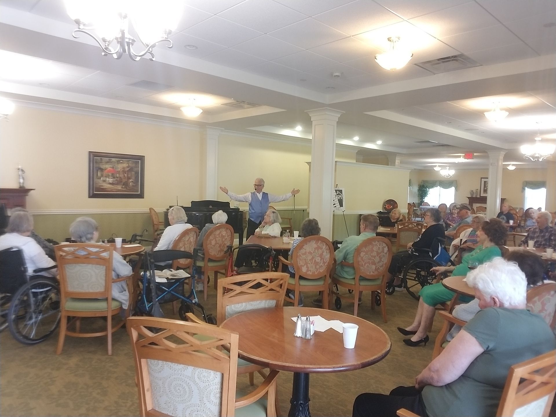 A man is giving a presentation to a group of elderly people in a dining room.