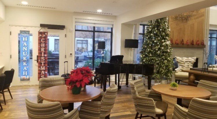 A living room with a piano , tables , chairs and a christmas tree.