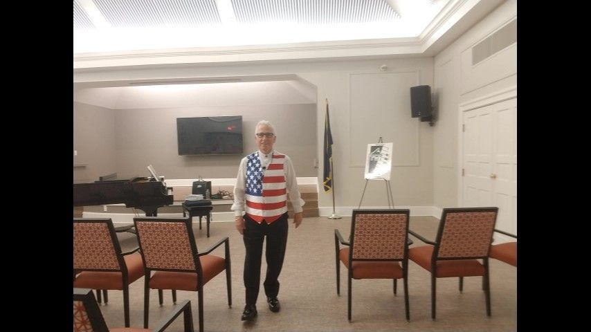 A man in an american flag shirt is walking in a room with chairs