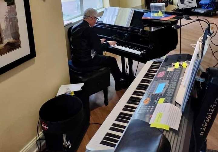 A man is playing a piano in a living room