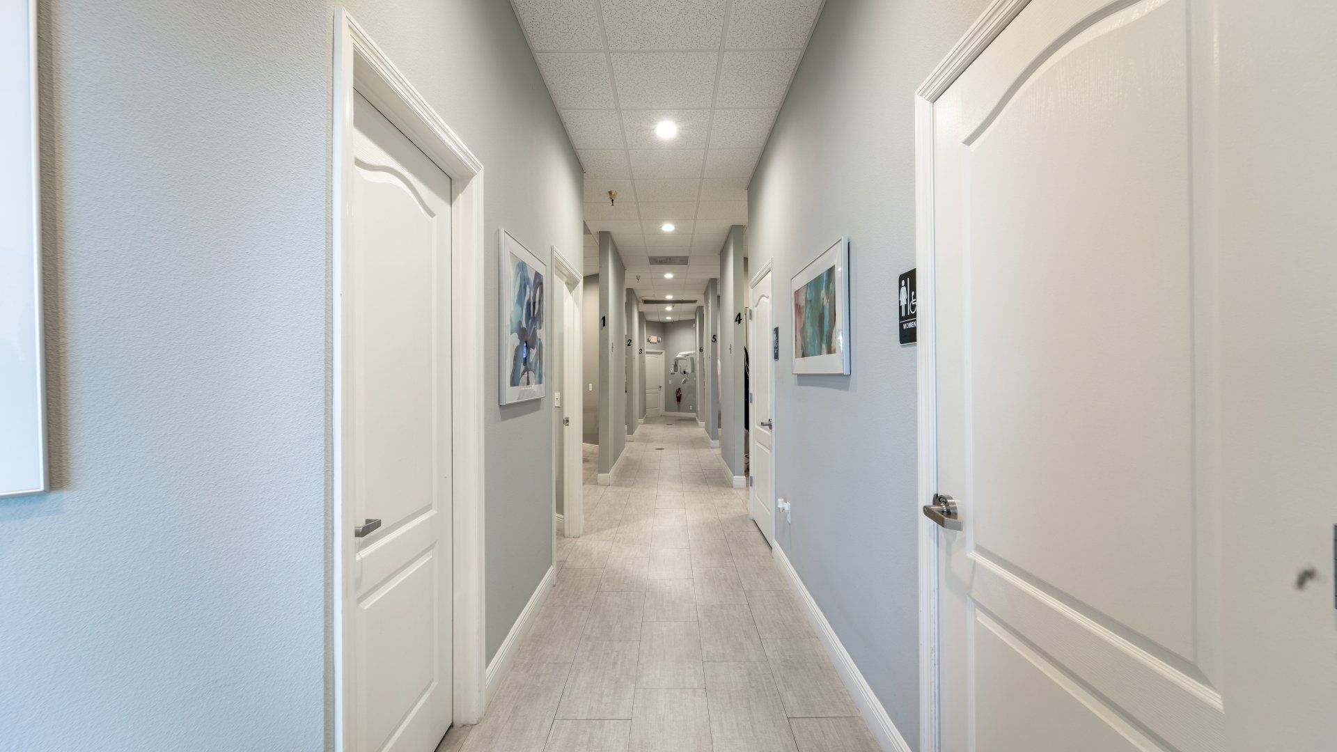 A long hallway with white doors and blue walls.