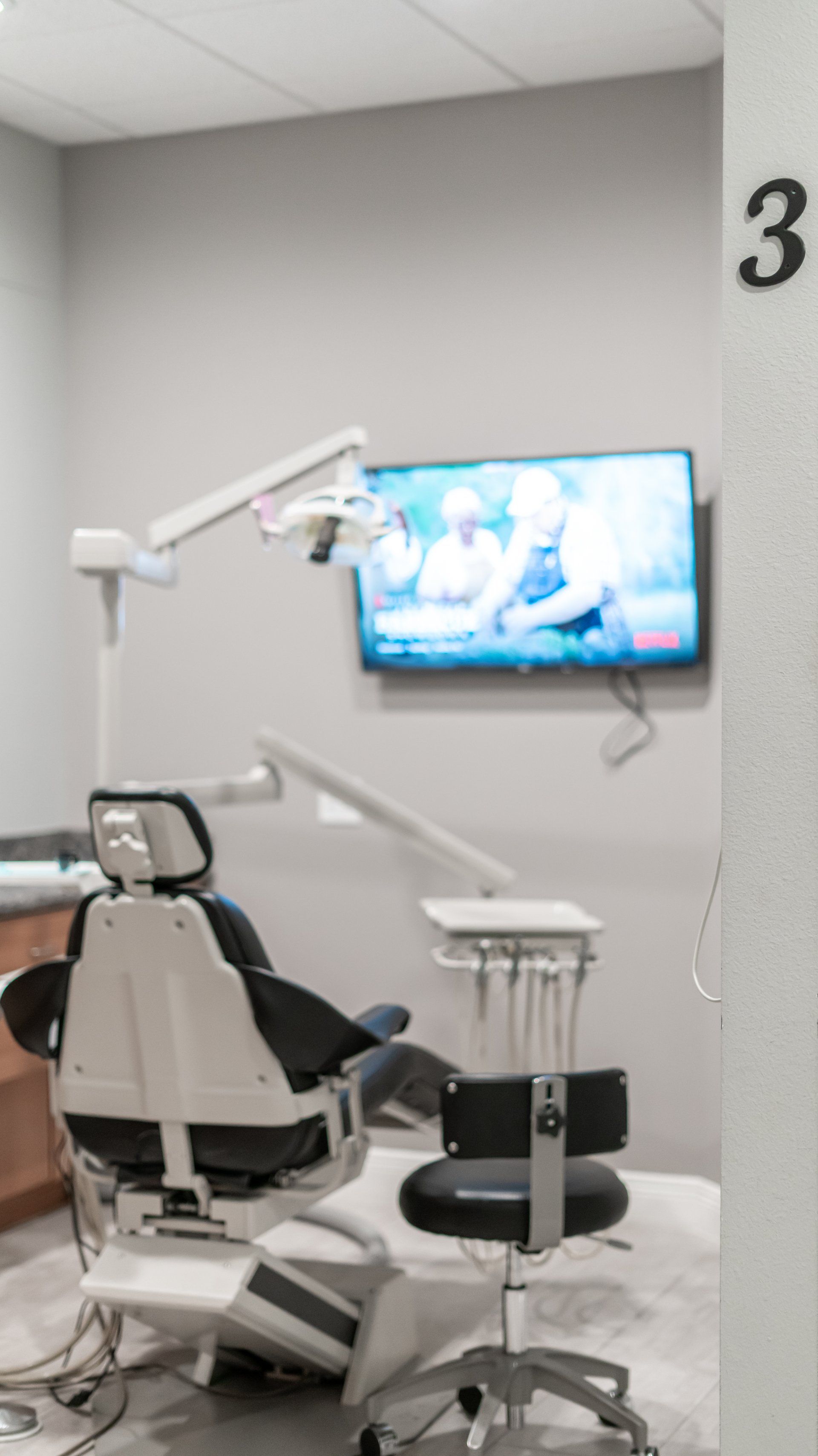 A dental office with a dental chair and a television on the wall.