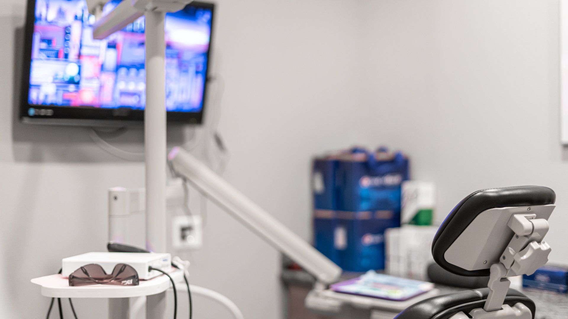 A dental office with a dental chair and a television on the wall.