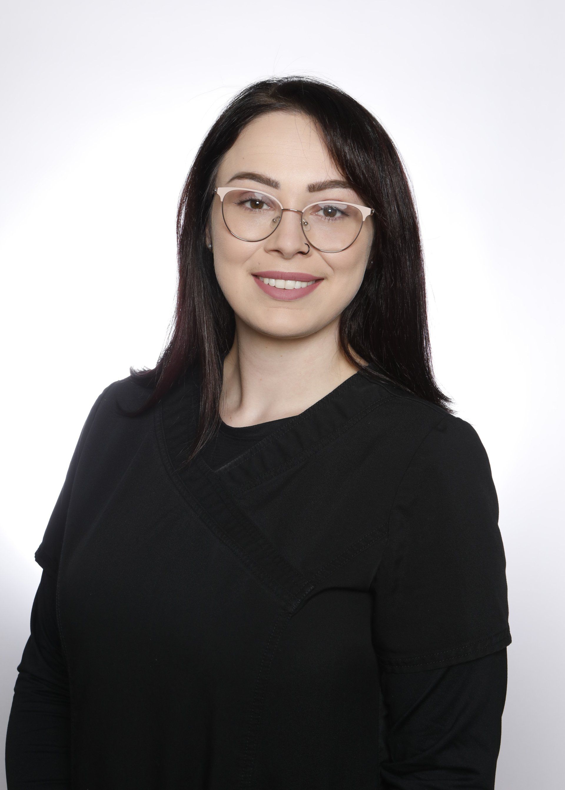A woman wearing glasses and a black shirt is smiling for the camera.