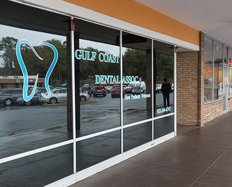 The outside of a dental office with a parking lot in front of it.