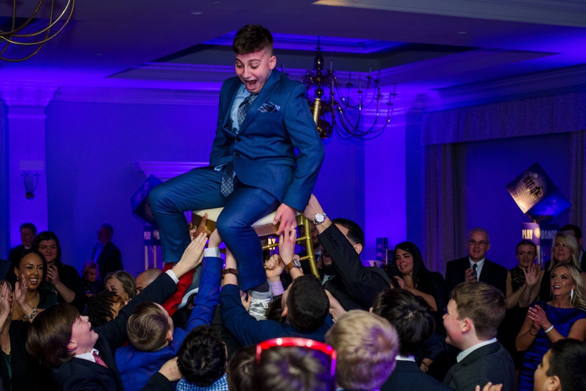 Bar Mitzvah chairlift ceremony with guests holding the boy high.
