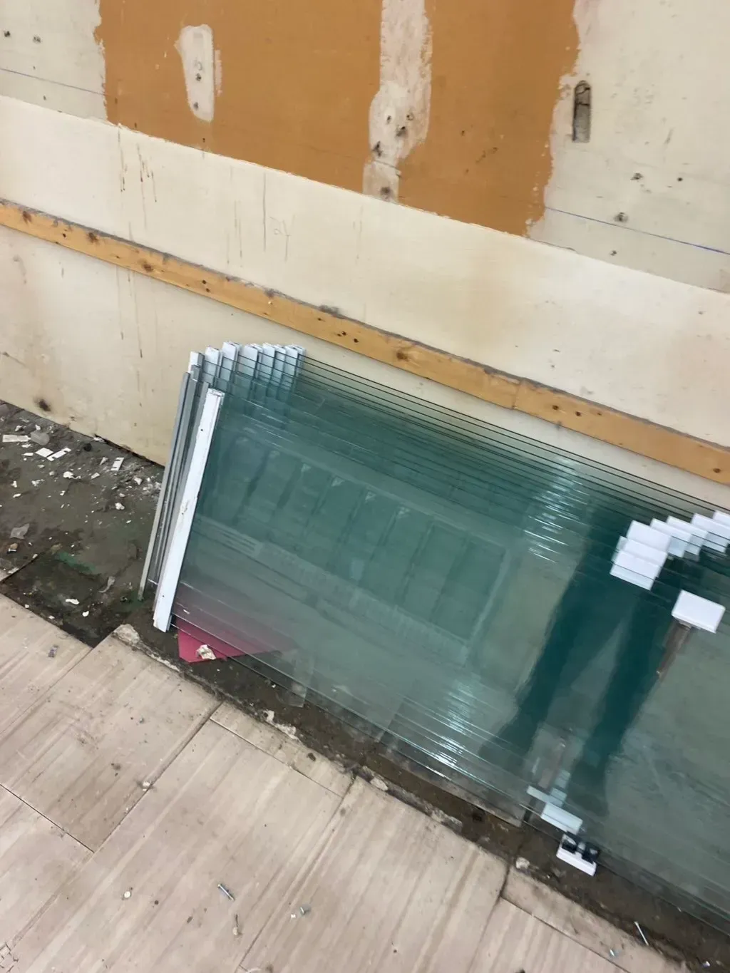 Stack of glass panels leaning against a damaged wall.
