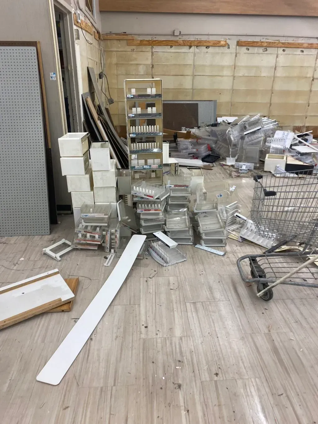 Interior view of a gutted store. Debris and fixtures strewn on the floor. Shelving is visible on the back wall.