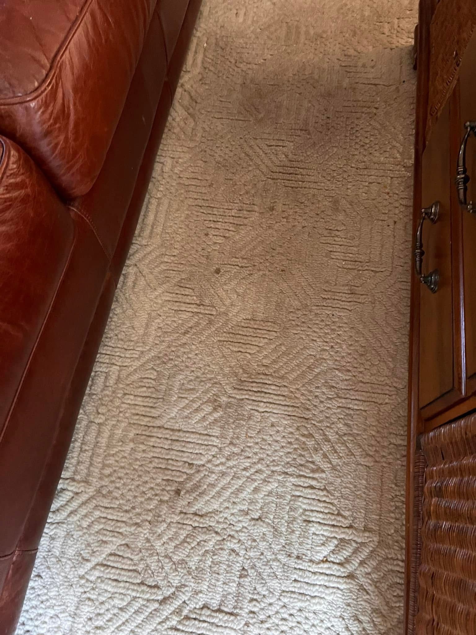 A living room with a brown leather couch and a tan carpet.