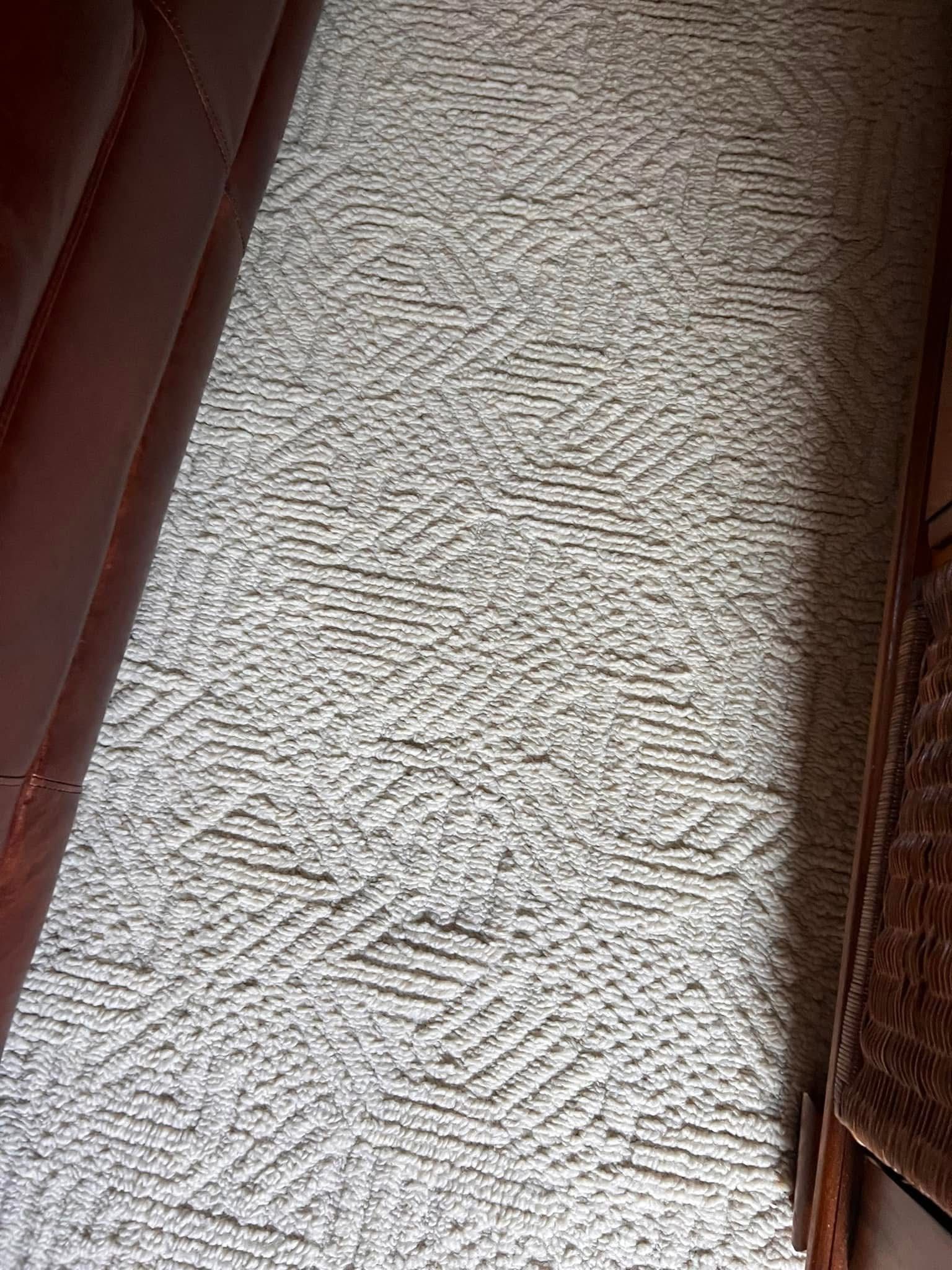 A white rug is sitting on the floor in a living room next to a couch.