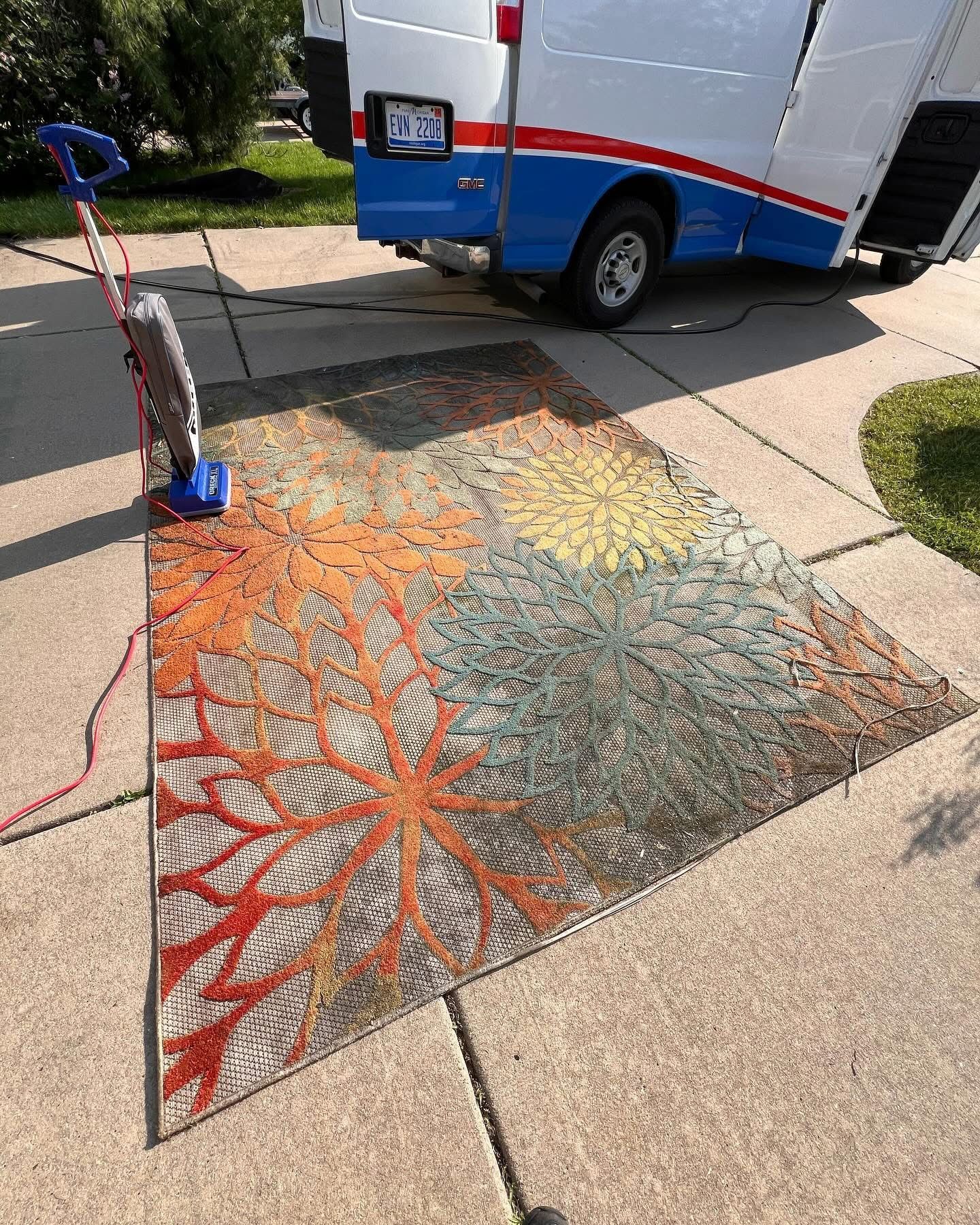 A rug is sitting on the sidewalk next to a truck.