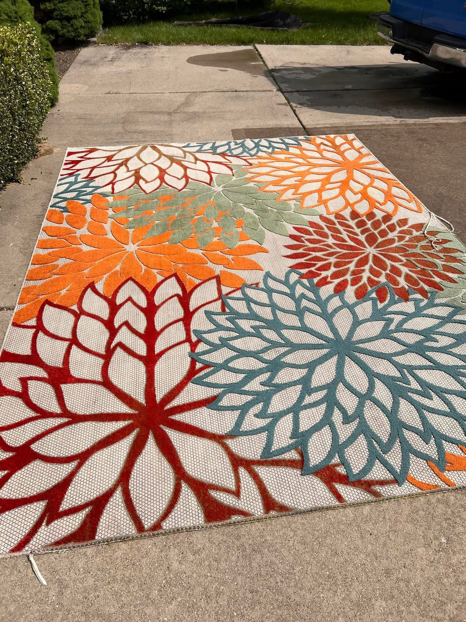 A colorful rug is sitting on the sidewalk next to a truck.