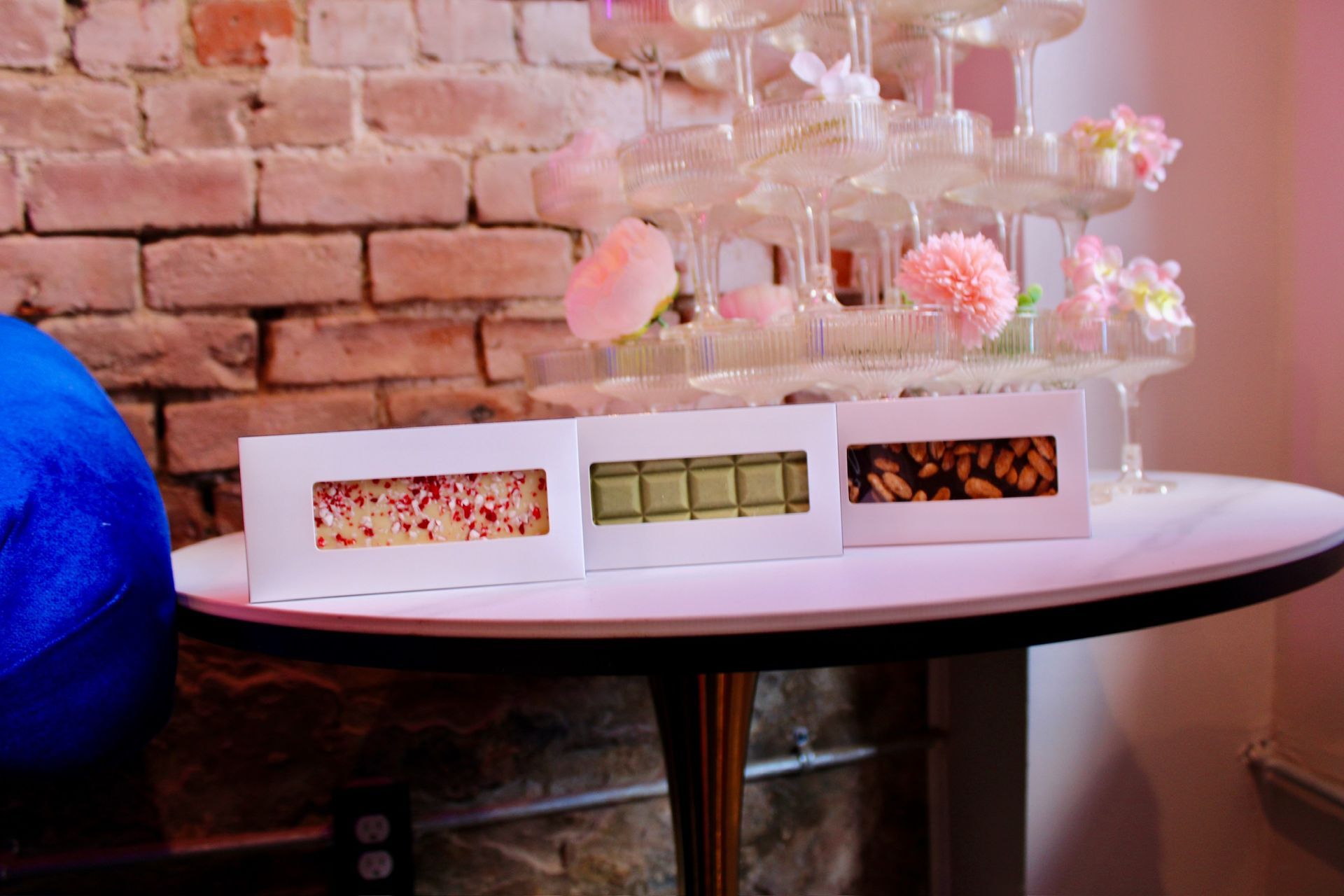 Chocolate bars on a table with a champagne tower and brick wall backdrop.