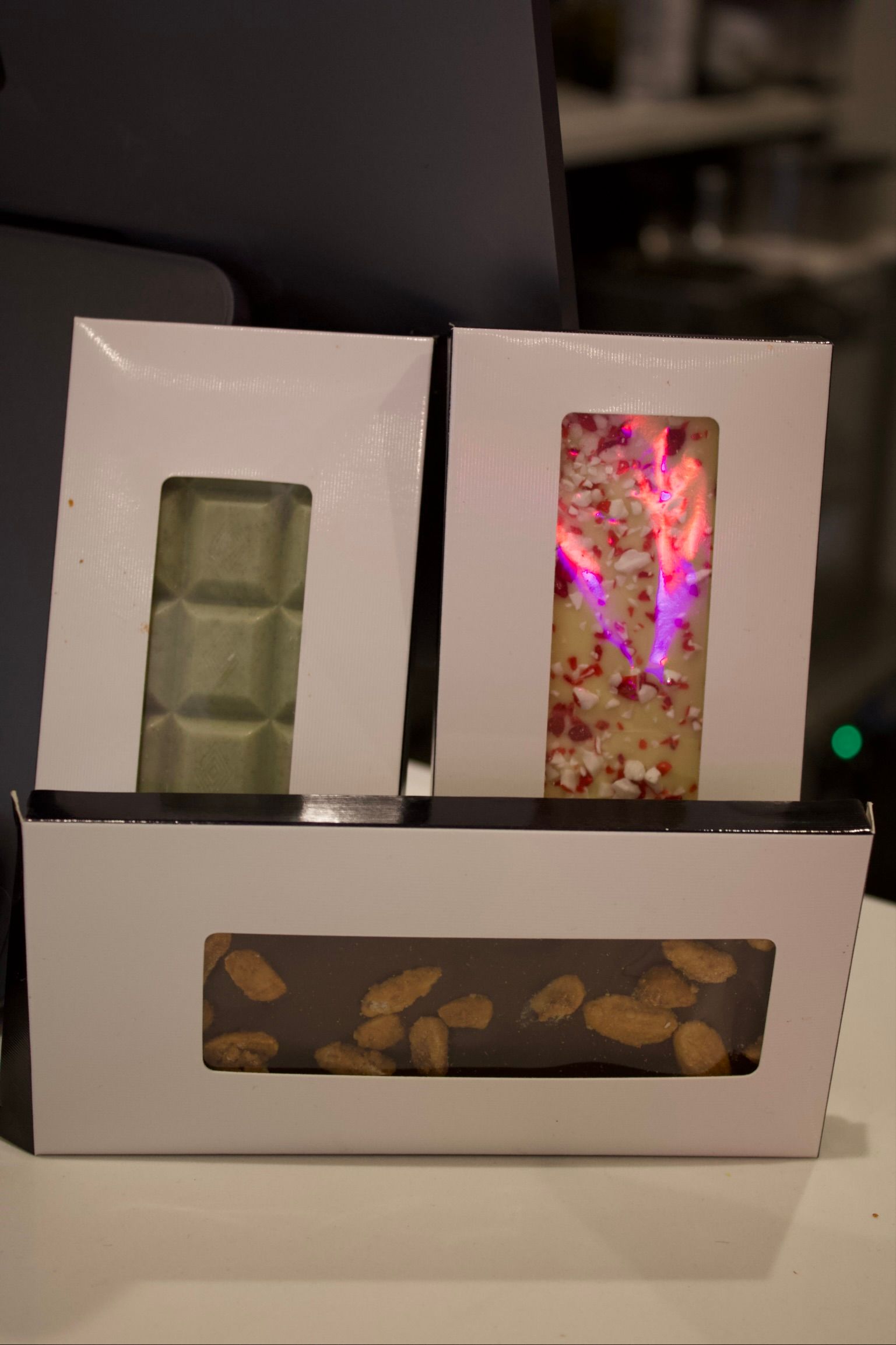 Three chocolate bars in white boxes with see-through windows.