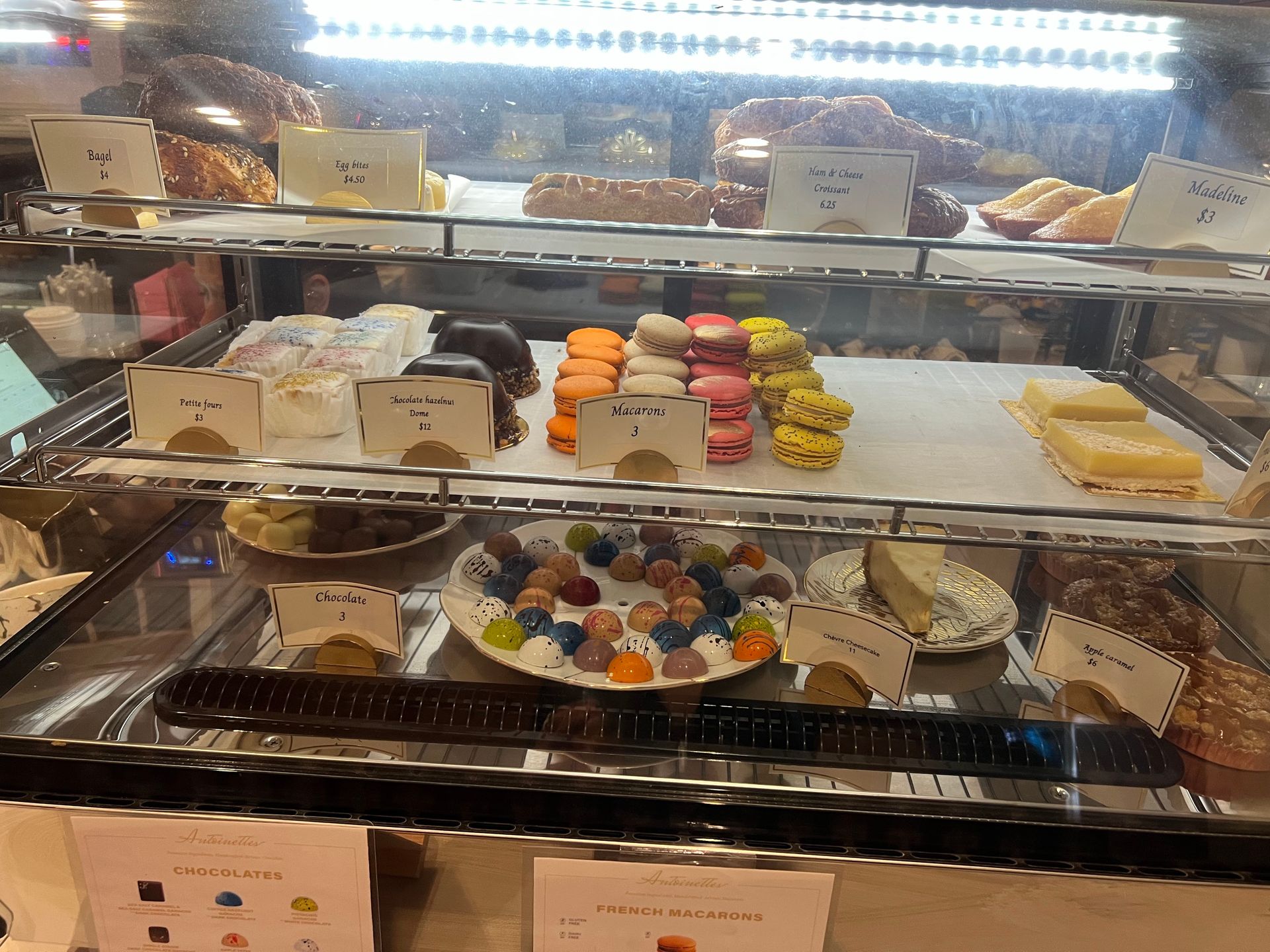 Pastry display case filled with colorful macarons, pastries, and treats.