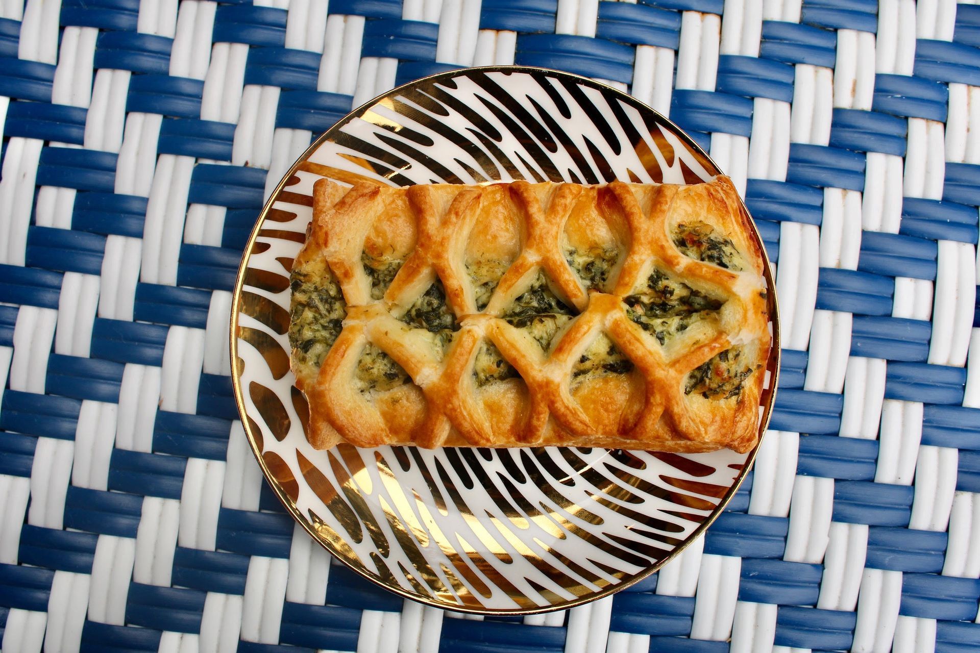 Pastry with green filling on patterned plate, set on blue and white woven mat.