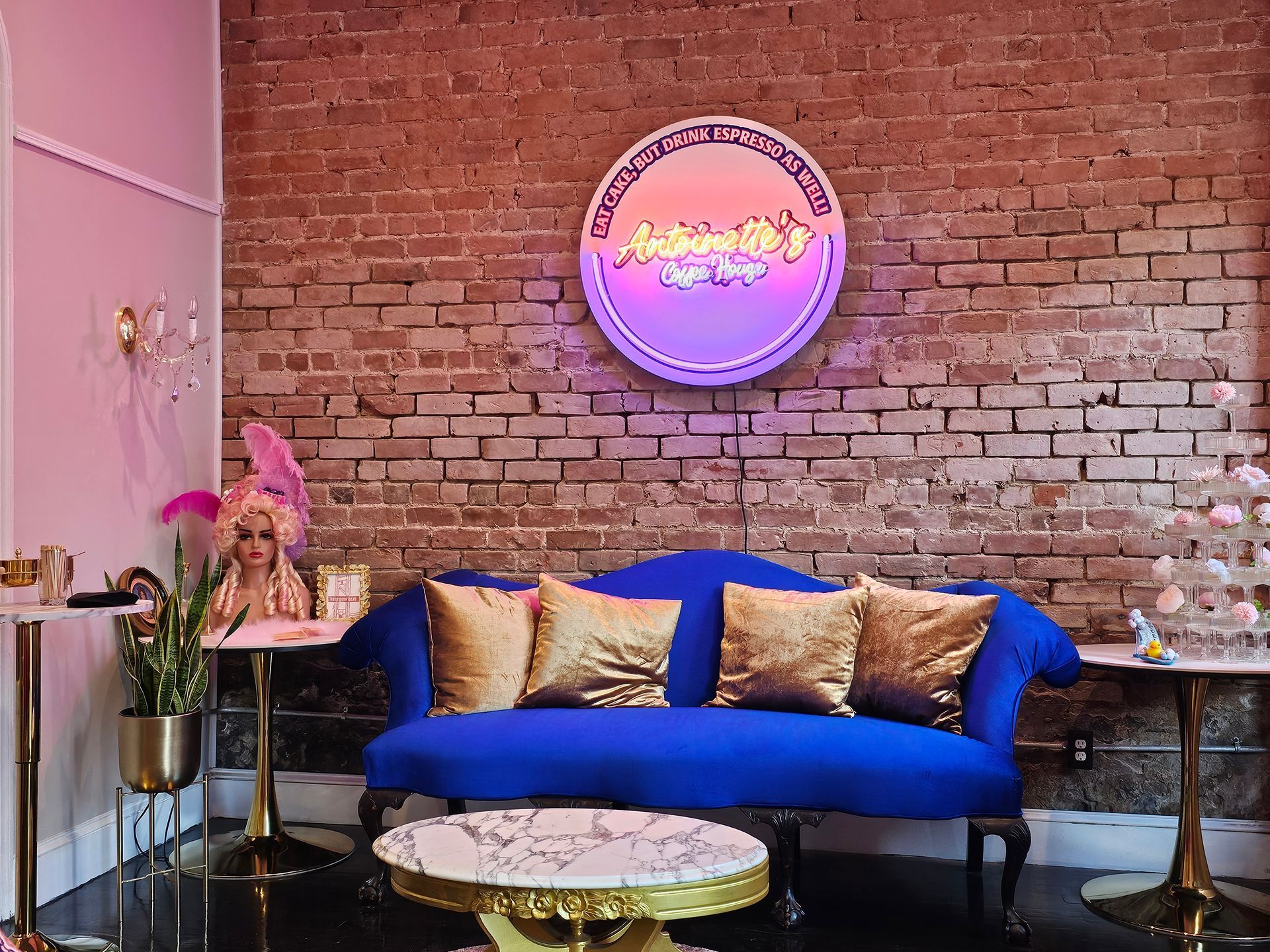 Blue couch with gold pillows, round logo sign, and brick wall.
