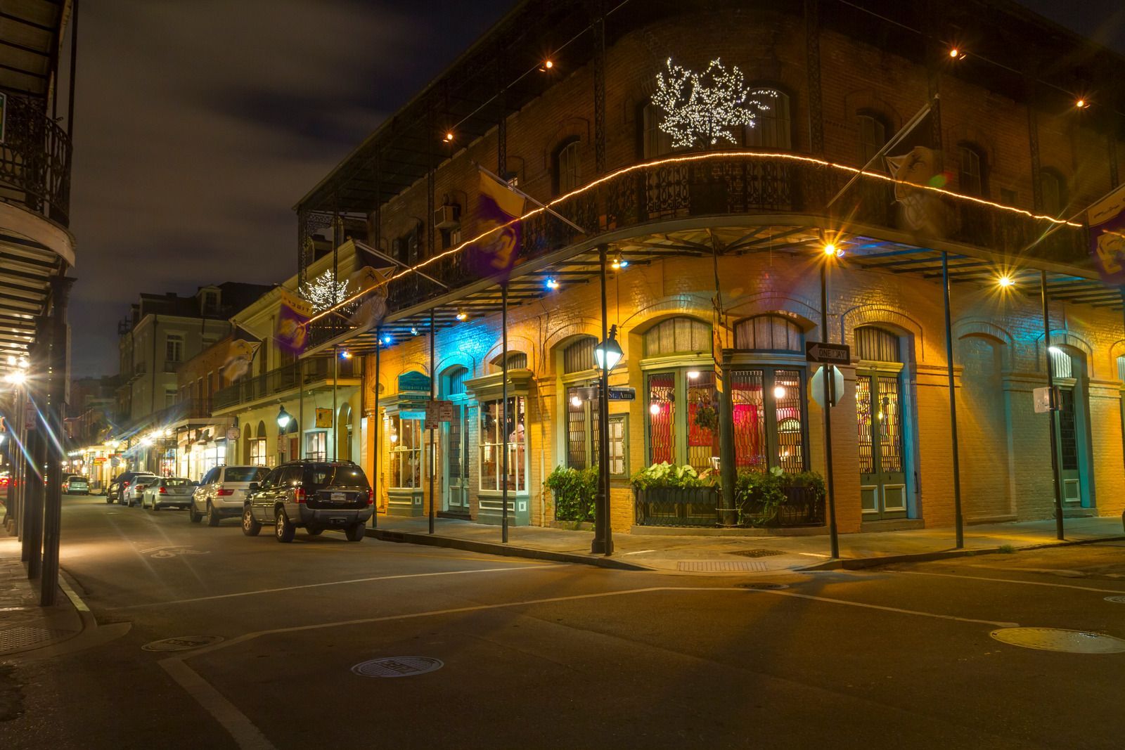 A city street at night with cars parked in front of a building.