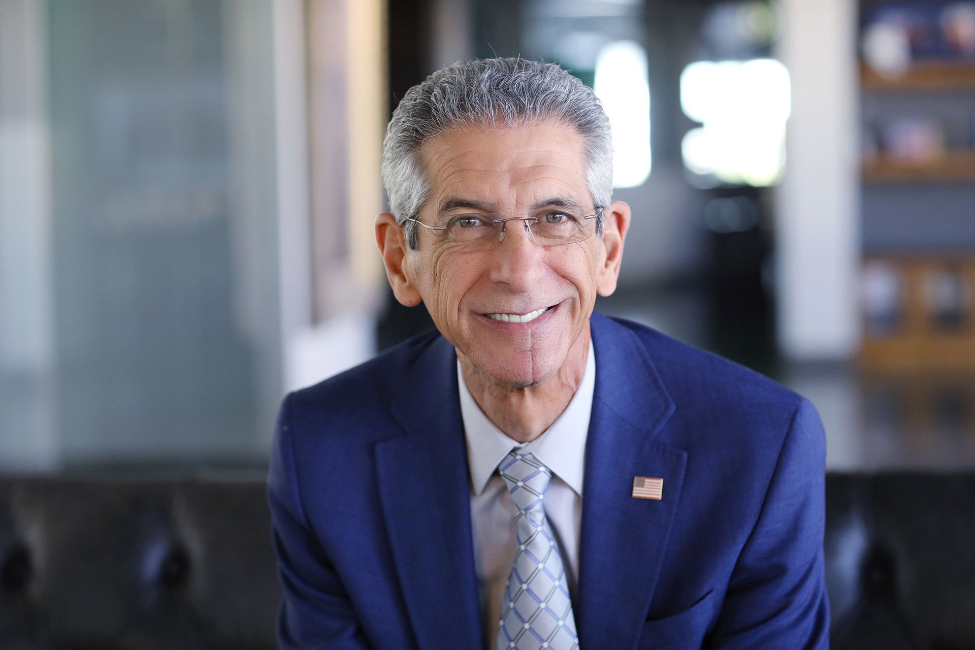 A man in a blue suit and tie is smiling for the camera.