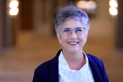 A woman wearing glasses and earrings is smiling for the camera.