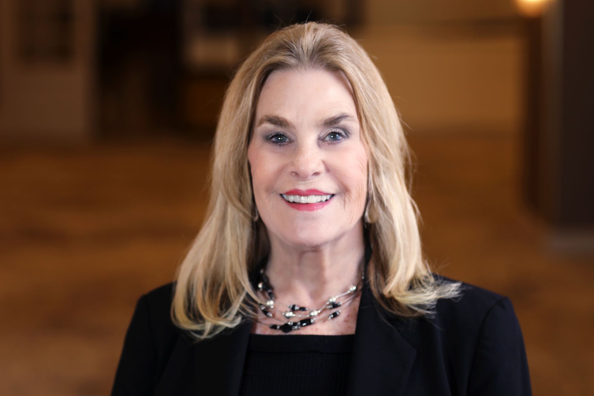 A woman in a black jacket and white shirt is smiling for the camera.